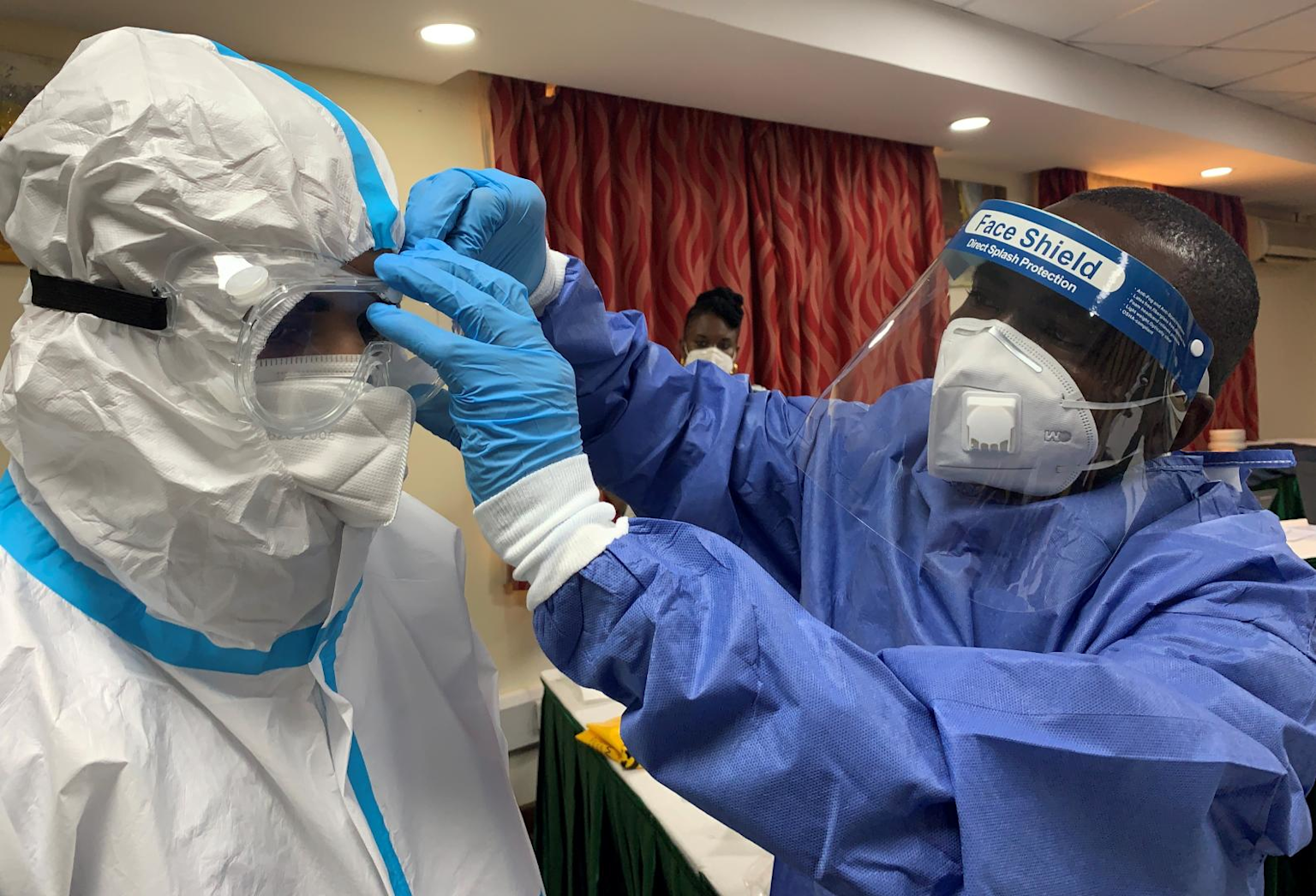 Healthcare workers in full PPE preparing for COVID-19 patient care in an African healthcare setting